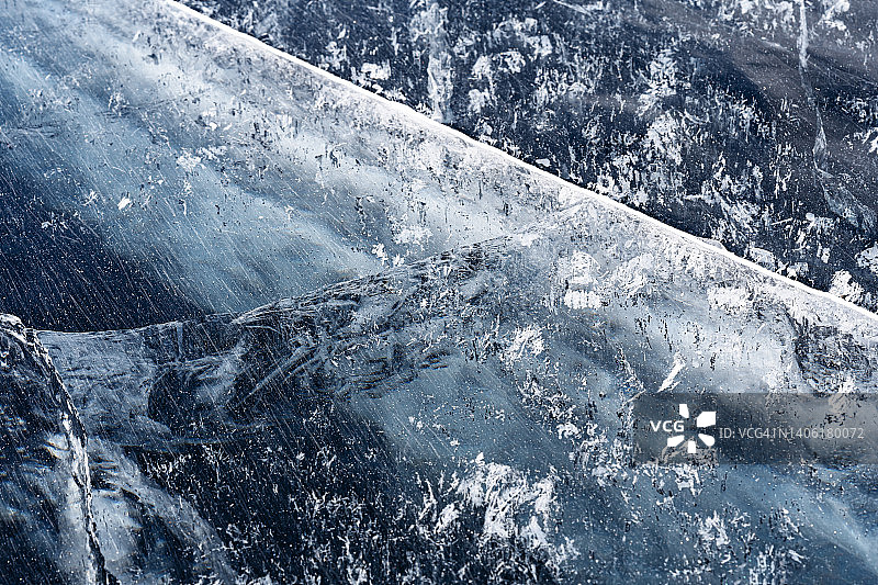 透明的深蓝色冰冻结贝加尔湖与白色的裂缝图案。图片素材