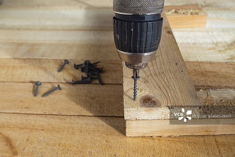 将螺丝拧入木板。自攻螺钉，螺丝刀钻和木板。居家生活，自己动手，DIY图片素材