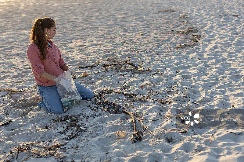 在海滩上收集塑料的年轻女性研究员图片素材