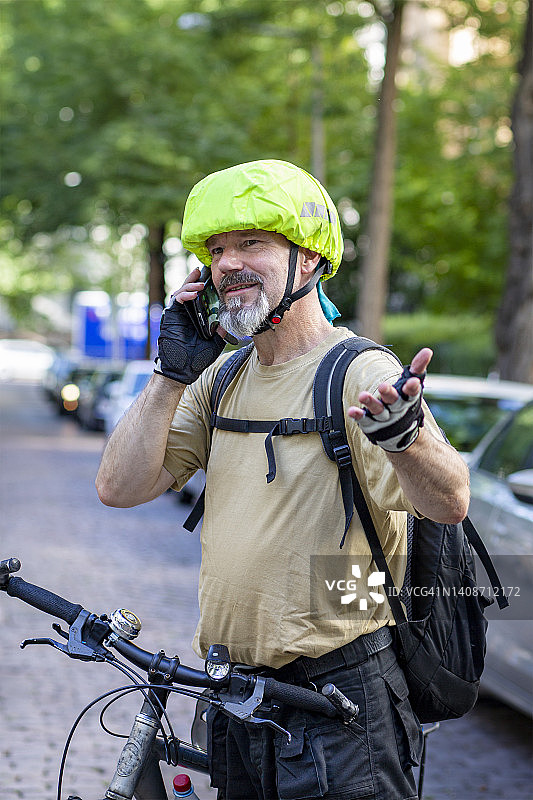 一名男子骑自行车用他的智能手机打电话图片素材