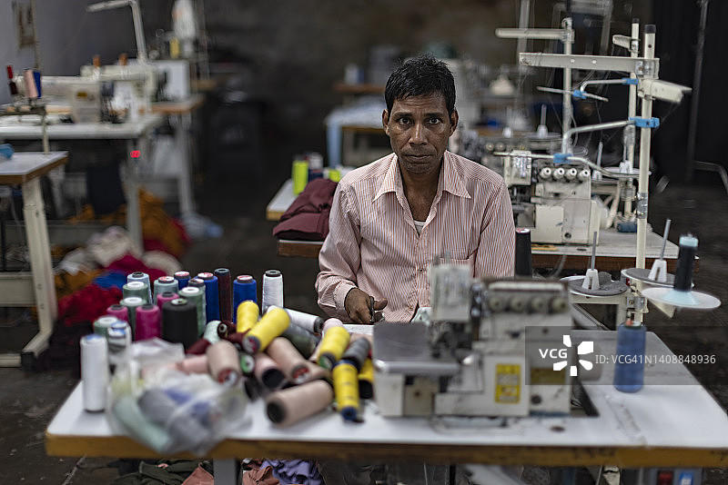 一个中年男子在纺织厂的机器上工作的肖像图片素材