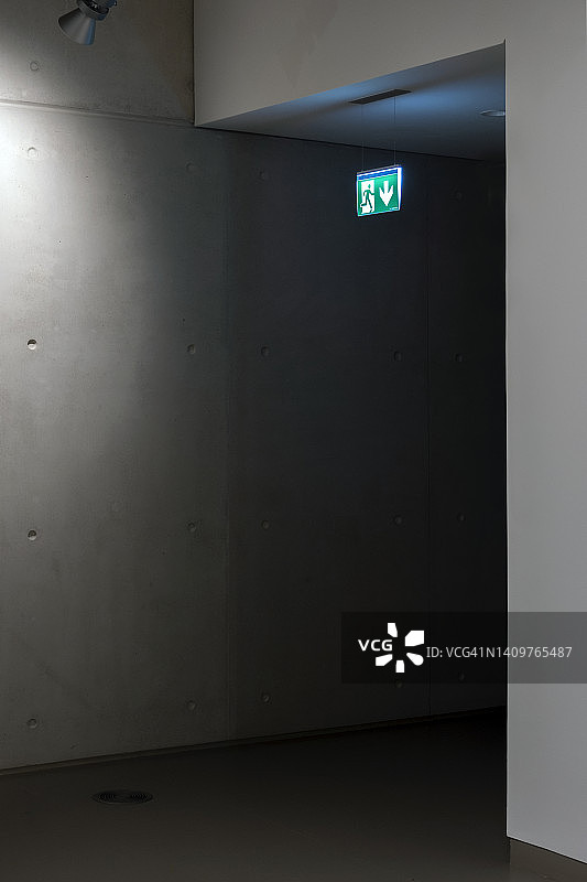 黑暗的走廊上挂着绿色出口标志图片素材