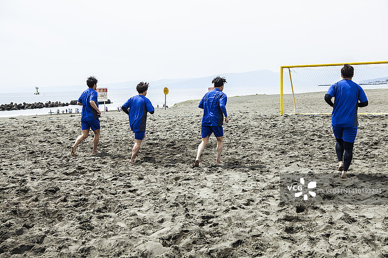四名球员在沙滩球场慢跑图片素材