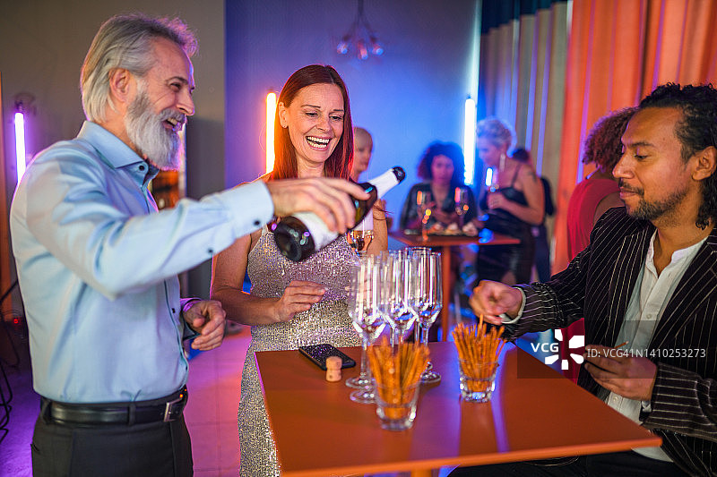一个成熟的白种人倒香槟在一个聚会上图片素材