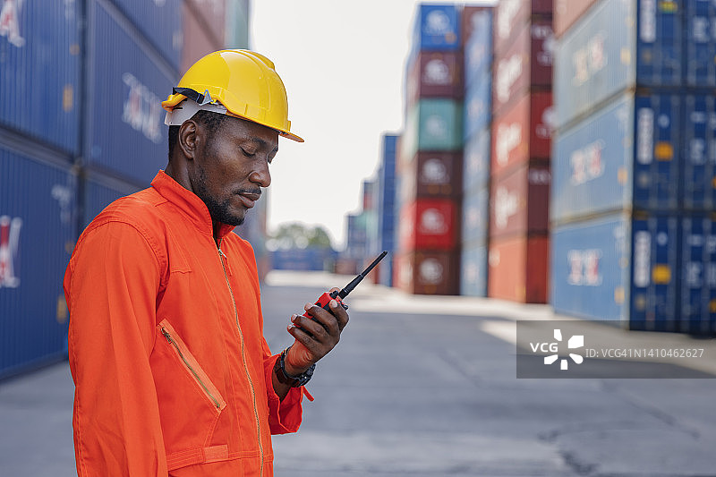 青年工人在集装箱仓库控制运输过程，用于企业物流，进出口运输或货物运输。图片素材