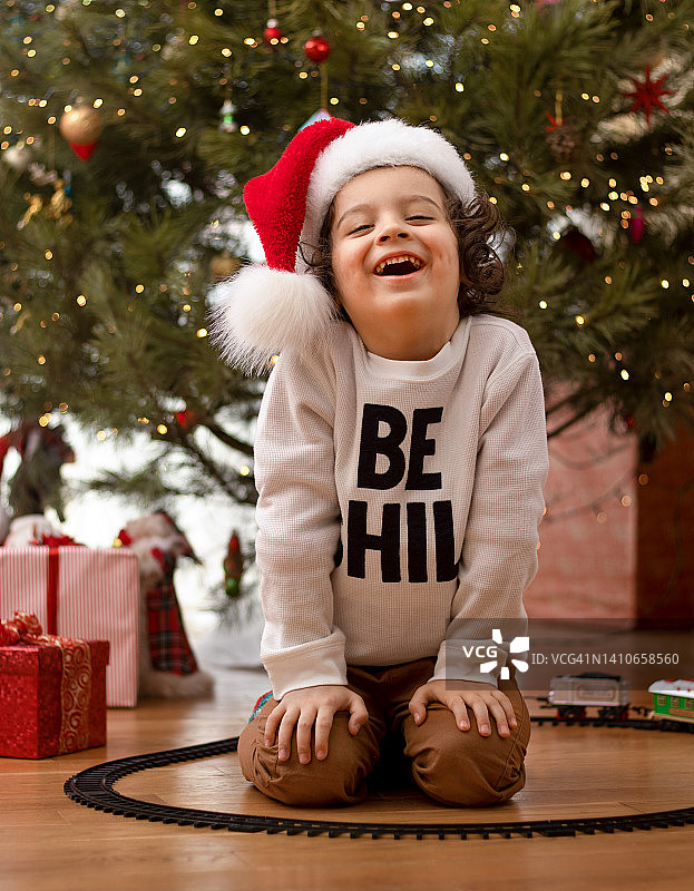 快乐的小男孩在圣诞树旁图片素材