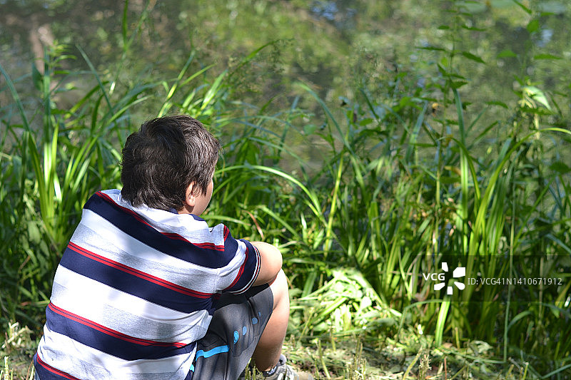 少年坐在湖边。图片素材
