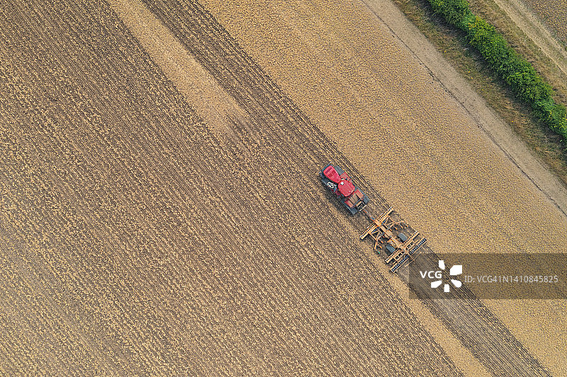 无人机拍摄的红色拖拉机在田间工作图片素材