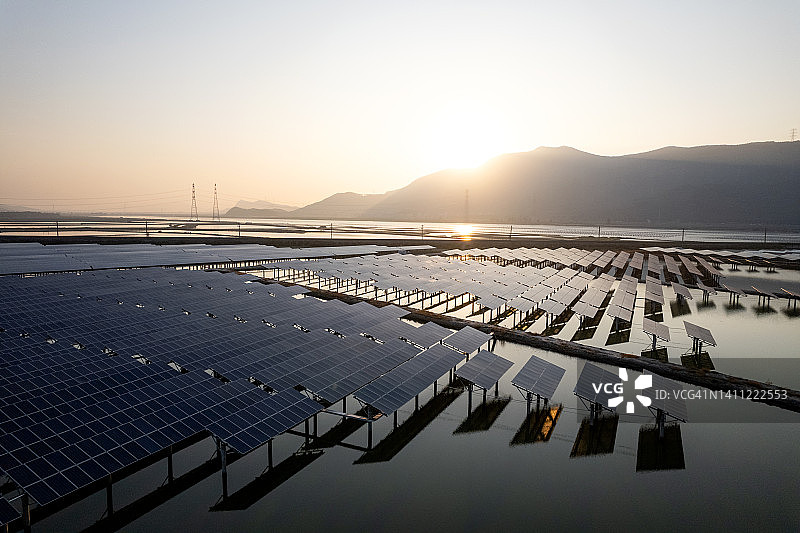 日出时水上太阳能发电厂的鸟瞰图图片素材