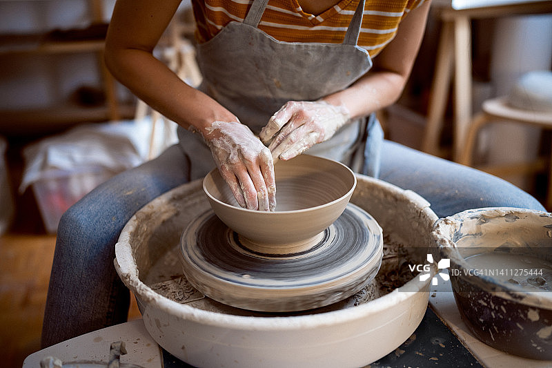 无法辨认的女陶工，在陶轮上工作图片素材