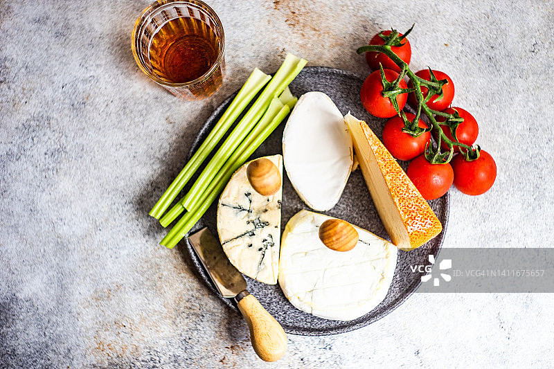 切菜板上各式各样的法国奶酪、西红柿、芹菜和面包，还有一杯甜点酒图片素材