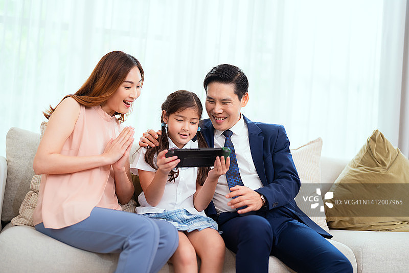 母亲，女儿和商人父亲一起玩电子游戏玩得很开心。图片素材