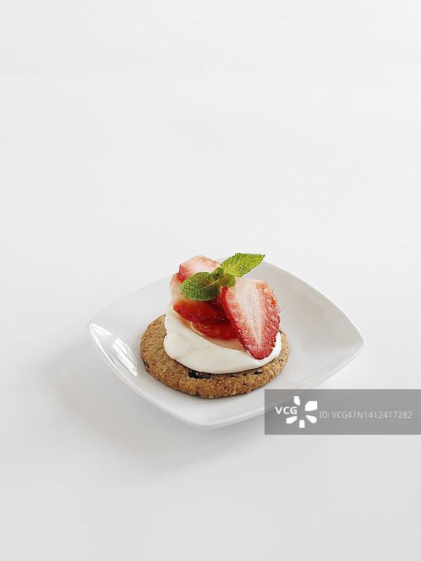 在白色的表面上撒上草莓和奶油的燕麦蛋糕图片素材