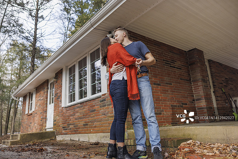 夫妻在他们的新家前接吻。以人为中心，以散焦为背景。图片素材
