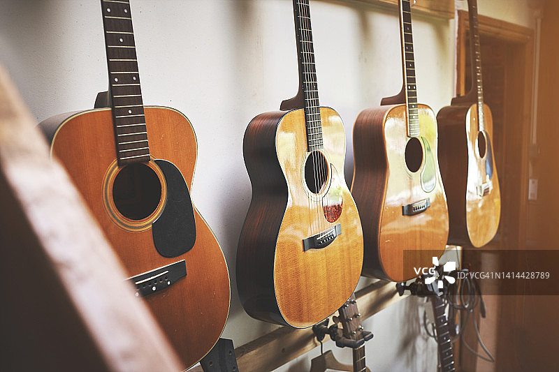 音乐商店里陈列的一组古典吉他乐器。当地一家新开的室内商店里，挂着用艺术木材制成的古典复古原声吉他或乐器。图片素材