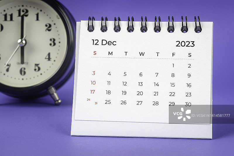 12月是组织者计划和截止日期的月份，一个闹钟在桌子上，蓝色的背景。图片素材