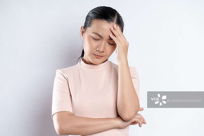 一名亚洲妇女因头痛而孤立地站在白色背景上。图片素材