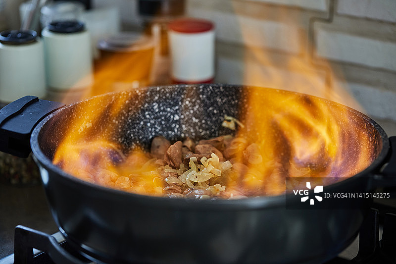 牛肉与洋葱在煎锅中炸，在煤气炉上燃烧图片素材