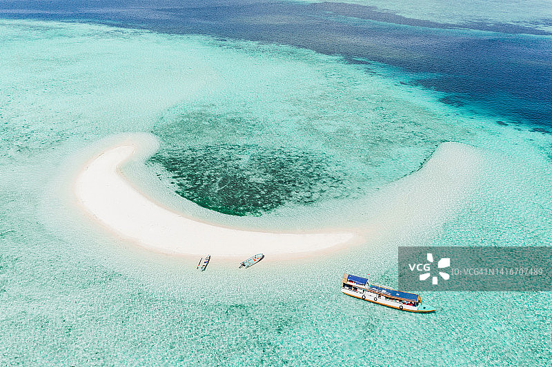 无人机查看珊瑚礁与热带白色沙滩小岛和游客潜水船。热带自然背景图片素材