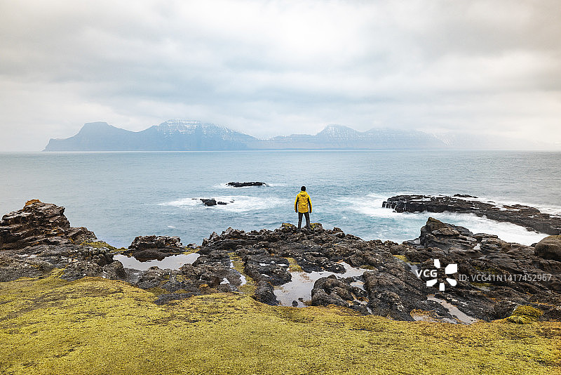 法罗群岛，Eysturoy, Gjogv，一名男性徒步旅行者在悬崖边欣赏大西洋图片素材