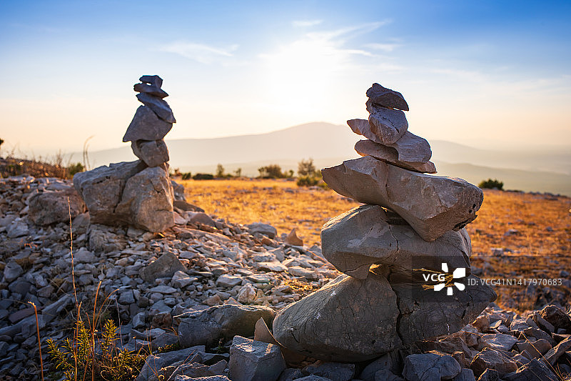 石头堆叠与平衡的石头在模糊的山背景在日落温暖的光股票照片图片素材