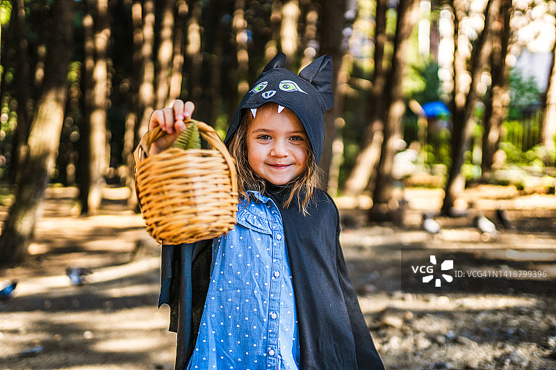 万圣节那天，小女孩穿着蝙蝠装在森林里散步图片素材
