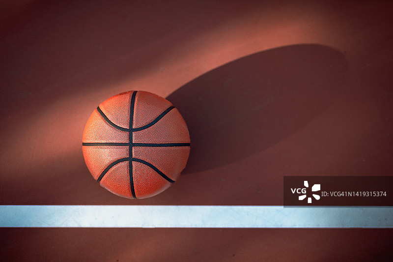 在硬地场上的篮球，用长长的阴影和线条作为运动和锻炼的象征图片素材