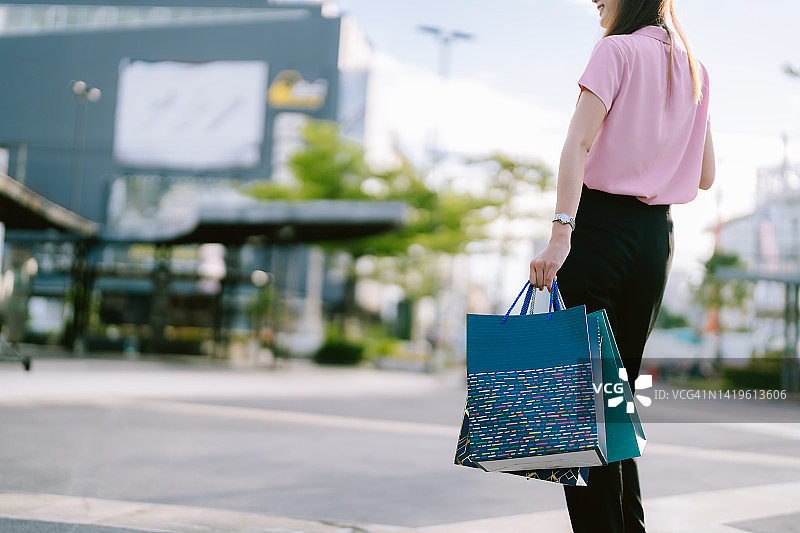 特写亚洲妇女的手拿购物袋在城市和购物中心。图片素材