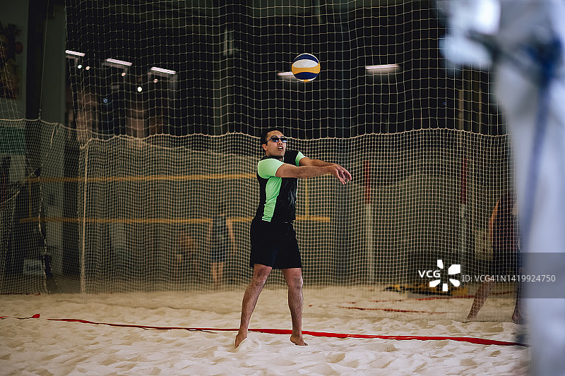 在室内打沙滩排球的男子肖像。生活方式运动摄影与人。多种族的人戴着太阳镜和球在健身房，就像在运动场上图片素材