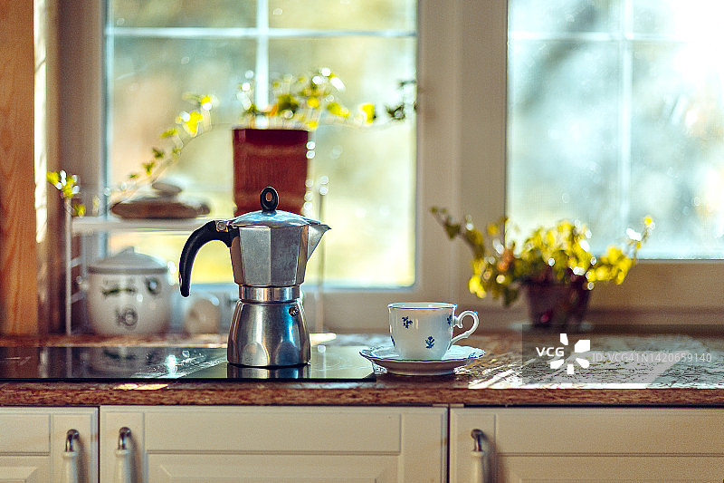 咖啡壶和咖啡杯放在窗户对面的炉子上。阳光明媚的早晨。乡村风格图片素材