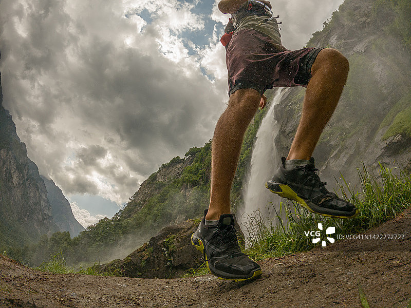男子跑步者跑过壮观的瀑布图片素材