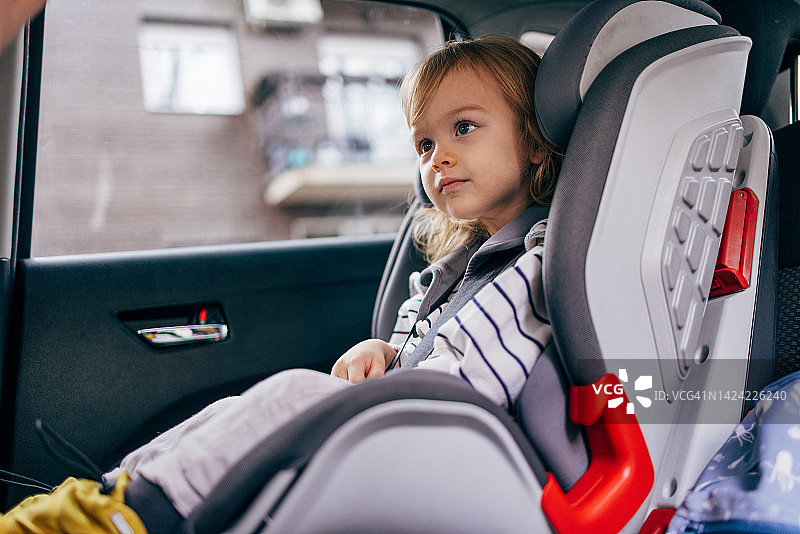 一个小女孩坐在汽车安全座椅上准备去旅行图片素材