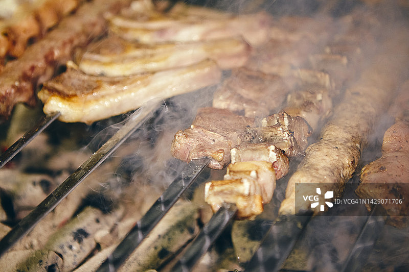 用不同类型的肉串在烤架上炸图片素材