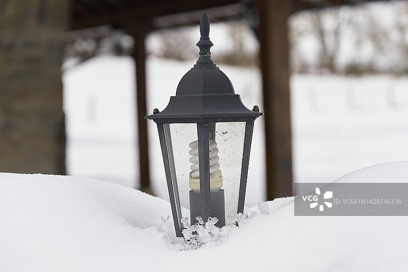 灯柱和灯泡被埋在雪中，背景中的房子和树有点模糊。图片素材