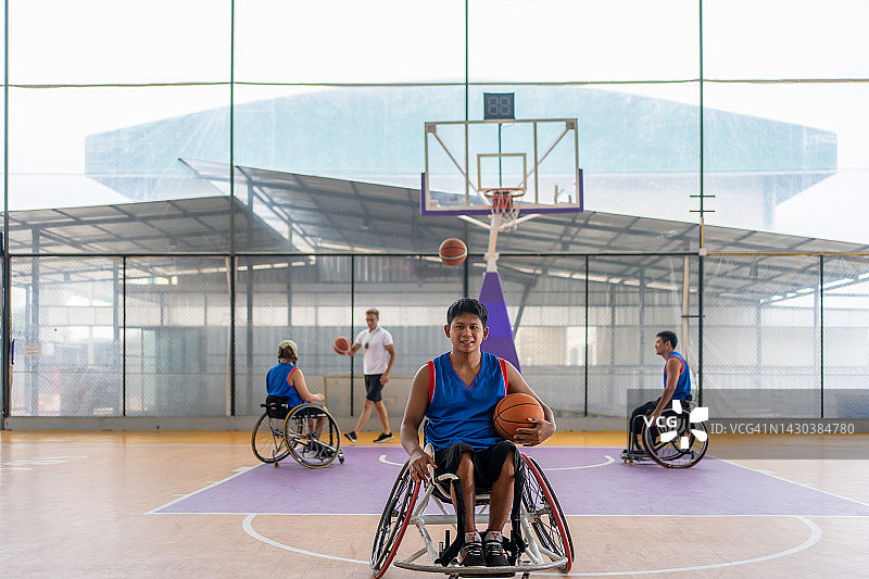 坐轮椅的篮球运动员在空地上拿球。图片素材