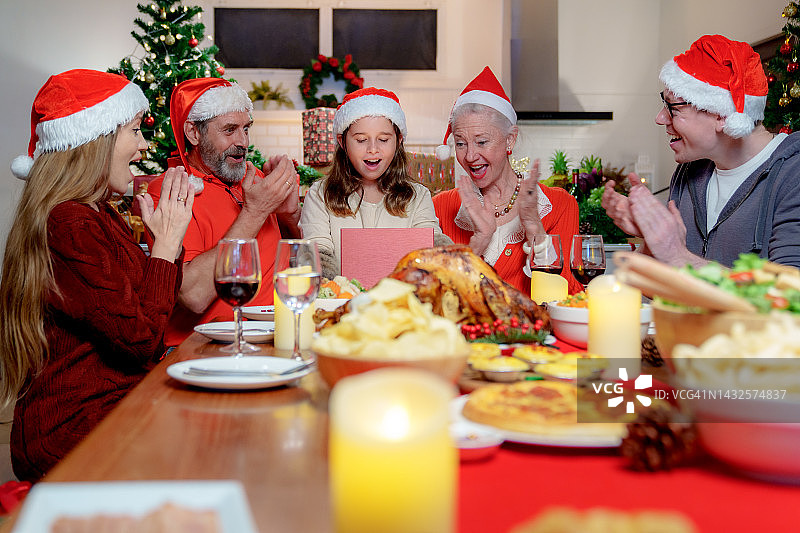 幸福的家庭一起享用圣诞大餐，交换礼物。庆祝节日，在树旁团聚。节日，庆祝和人的概念。图片素材