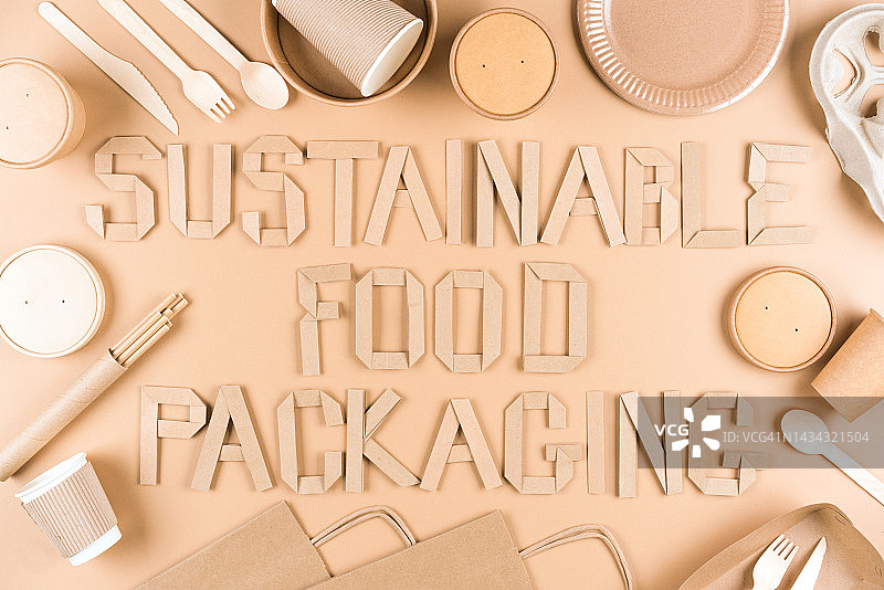 文字可持续食品包装-纸器具，木制餐具套，纸杯，盘子，袋和食品容器在浅棕色背景。平躺风格图片素材