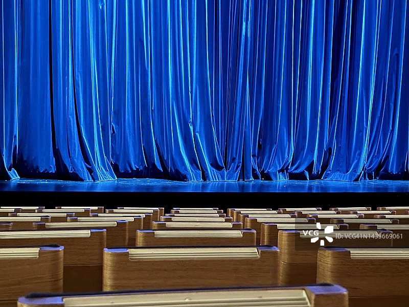 空荡荡的剧院座位和拉上的蓝色舞台幕布图片素材