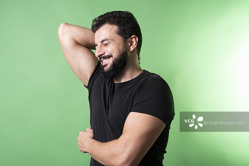 男人在工作室绿色的背景微笑和姿势图片素材