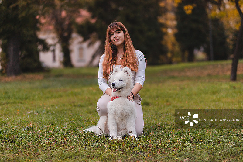 可爱的萨摩耶小狗和它的主人在公园外面合影图片素材