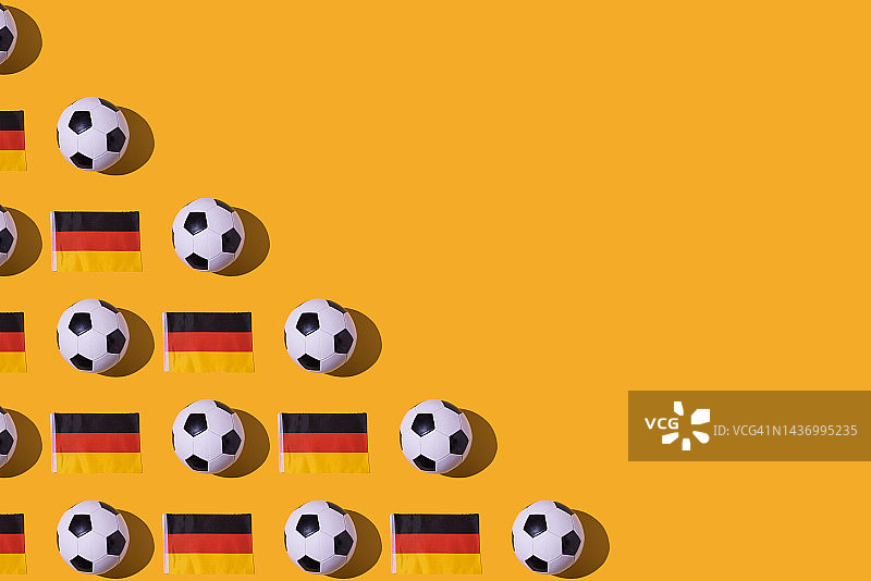 老式足球的图案旁边的德国国旗，黑色，红色和黄色，在左边，在一个黄色的背景。足球，足球世界杯，体育，比赛和世界冠军的概念。图片素材