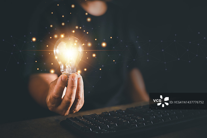 人手握电灯泡，用电脑键盘，新观念，新创意，企业管理的创新与灵感。图片素材