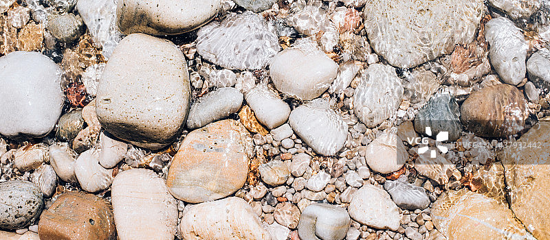 大海里的鹅卵石的自然背景。不同大小和不同颜色的鹅卵石。假期。放松。夏天。图片素材