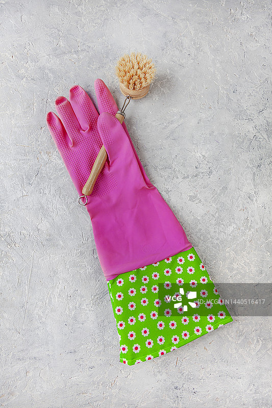 可重复使用的粉红色橡胶手套做家务和生态友好的木制洗碗器在灰色的混凝土背景。清洗设备。零浪费的概念。图片素材