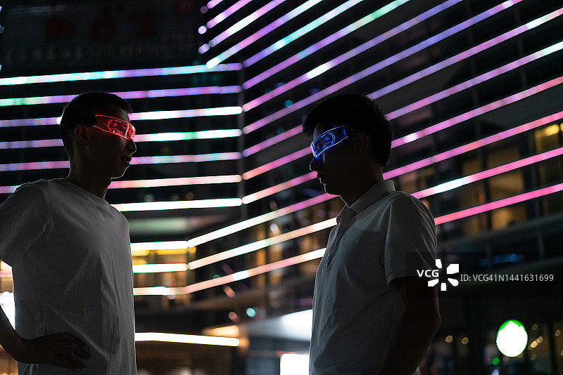 一名男子在城市霓虹灯背景上使用虚拟现实眼镜图片素材