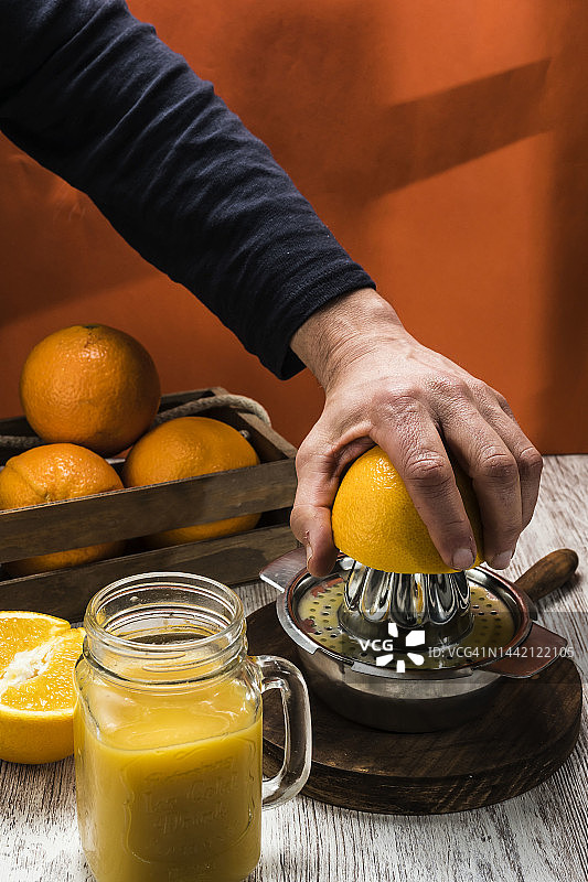 正在制作新鲜橙汁的人，背景是橙子图片素材