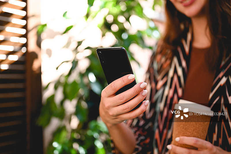 商业女性使用智能手机，手持可重复使用的环保生态杯图片素材