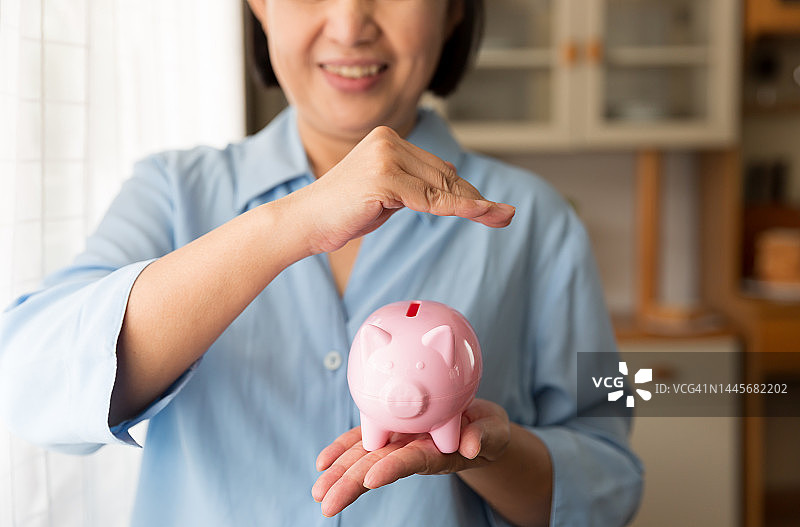 老妇人抱着存钱罐。为未来储蓄和投资的概念图片素材