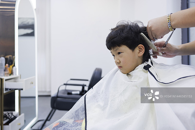 这个耐心的小男孩在理发店剪了头发图片素材