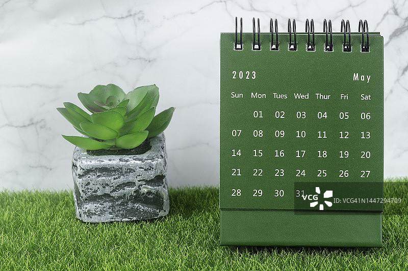 日历桌2023:五月是组织者计划和截止日期的月份，在大理石混凝土背景下放置室内植物。图片素材